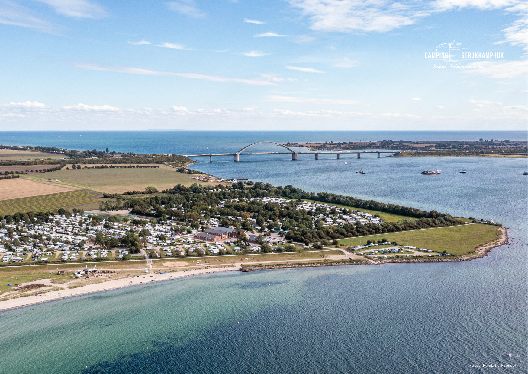 Campingplätze: Ein Blick von oben zeigt die Nähe zur Ostsee, die ikonische Fehmarnsundbrücke und die weitläufigen Stellplätze unseres Campingplatzes. - Camping Strukkamphuk